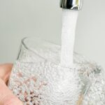 closeup of a young caucasian man filling a glass of tap water